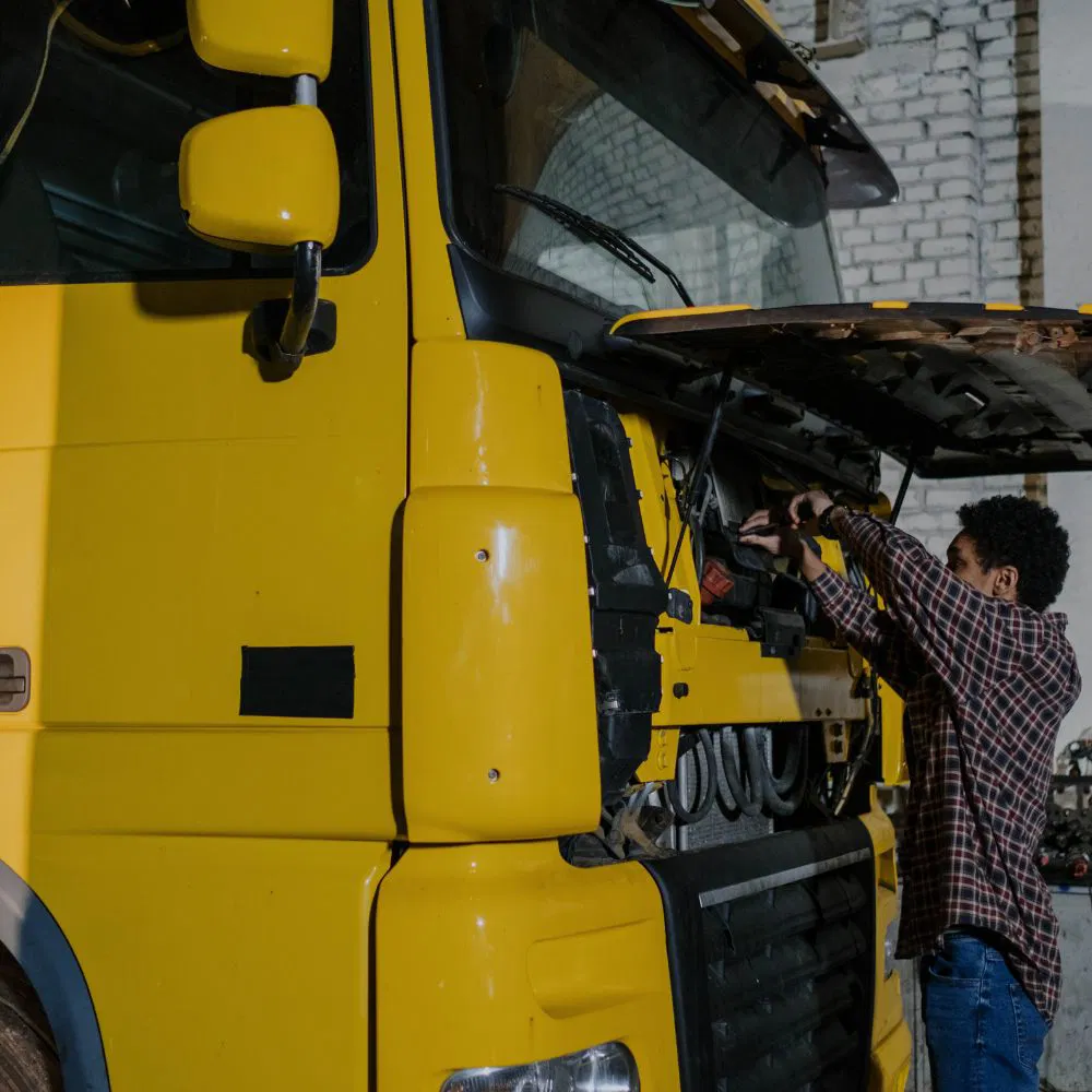 A man repairing the fuel system of a commercial truck.